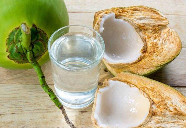A glass of water next to a coconutDescription automatically generated